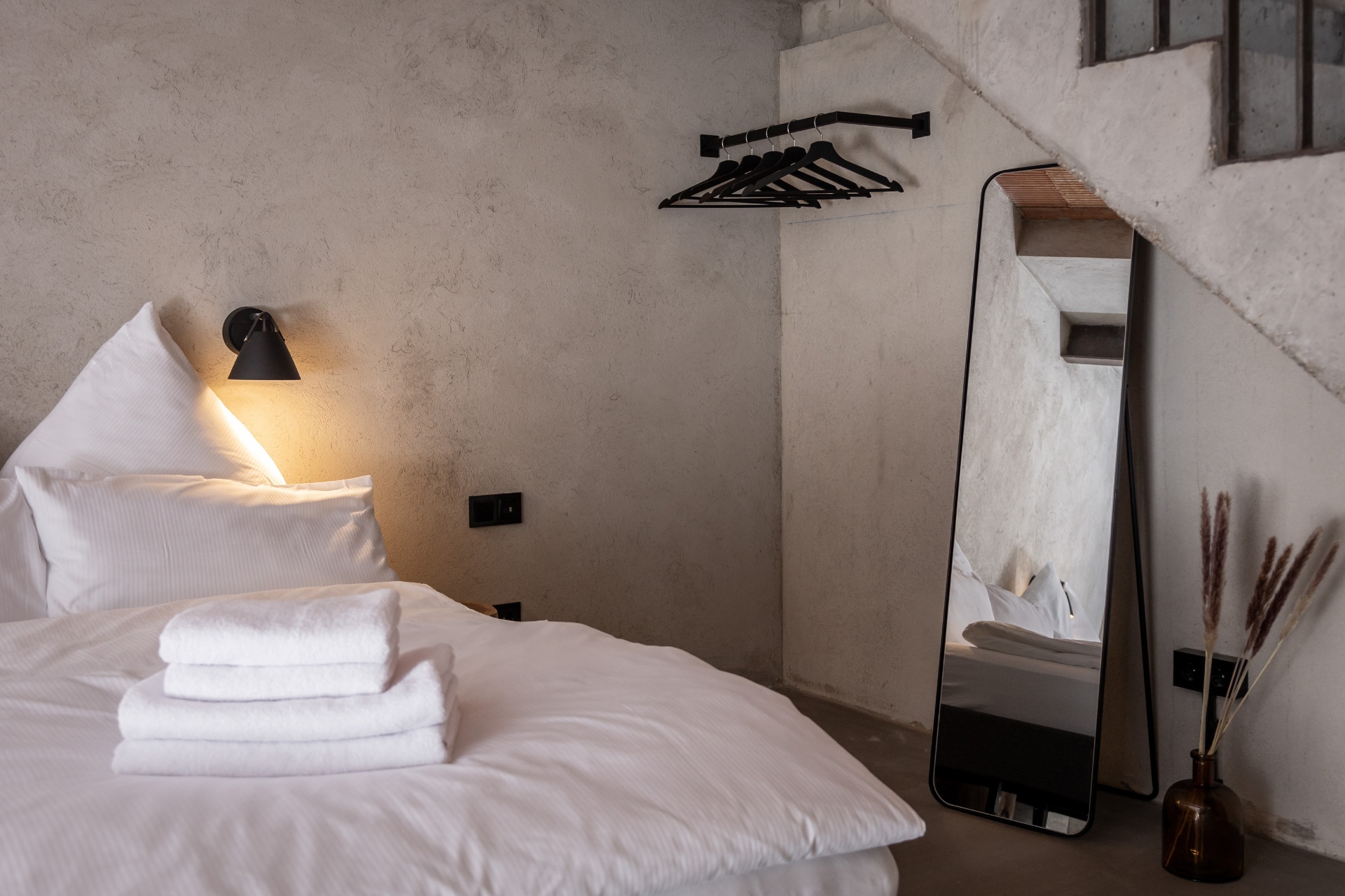 Industrial loft bedroom in Berlin with concrete walls and warm linen bedding